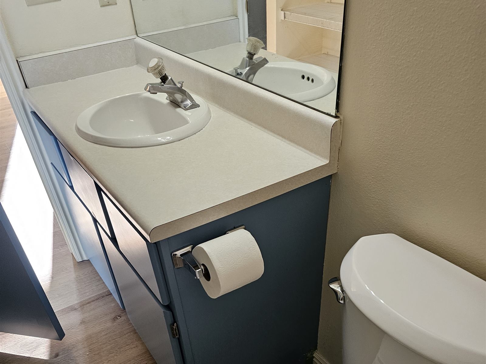 Refreshed bathroom with repainted vanity, new toilet, and new flooring