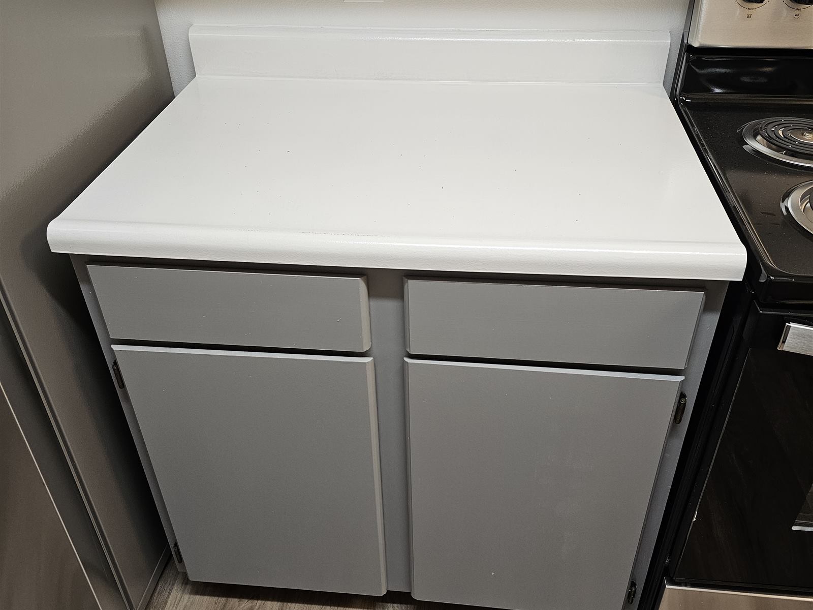 The same kitchen corner finished with a new white countertop and refinished gray cabinets