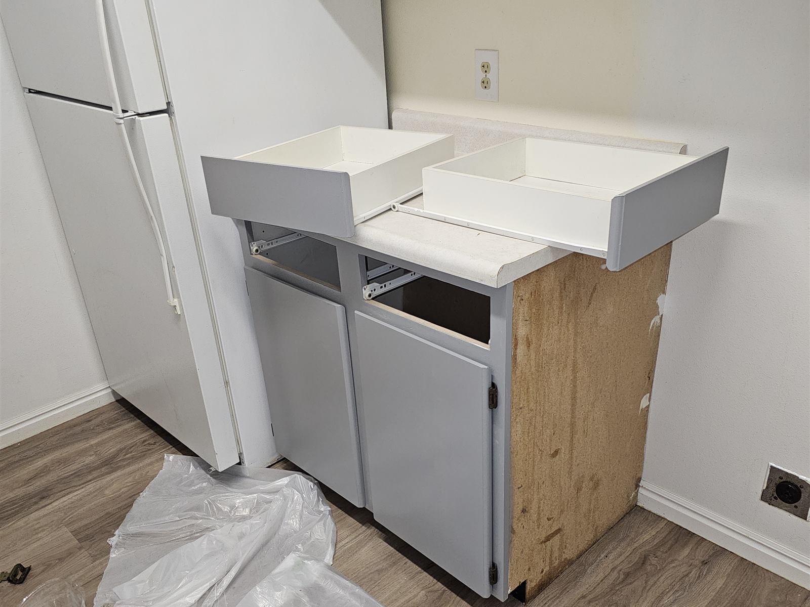 Kitchen corner cabinet mid-refinish with the countertop removed and doors freshly painted